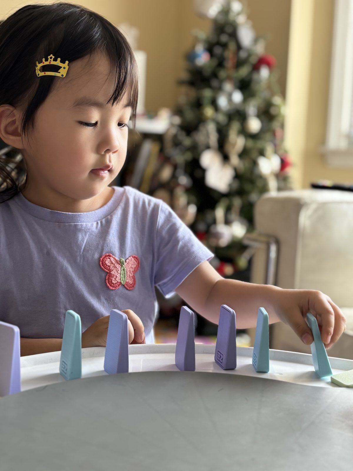 A child placing colorful EZ Domino pieces in a row on a play table