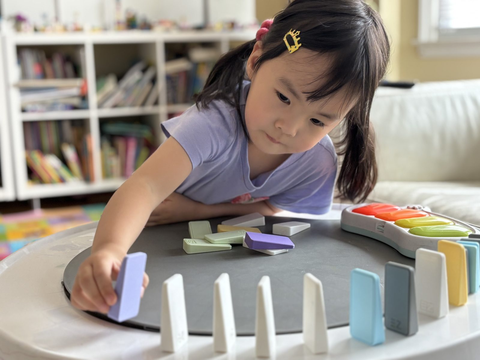 A child arranging EZ Domino pieces in a circular pattern on a play tray